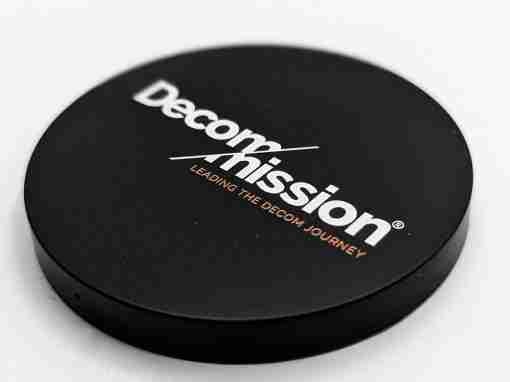DecomMission Branding Coaster Black coaster with the DecomMission logo and tagline printed on it.