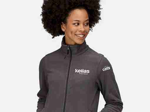 Kellas Branded Gray Fleece Jacket Woman wearing a gray fleece jacket with Kellas branding on the front and cats logo on the sleeve.