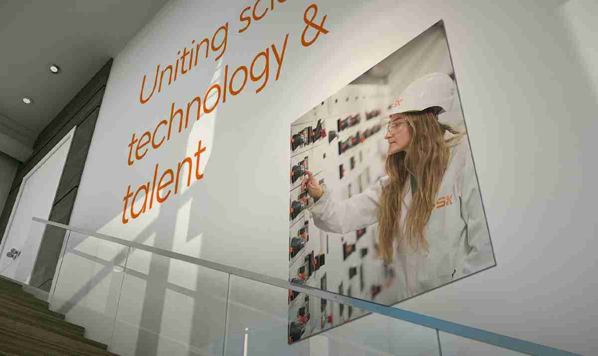 Wall mural featuring a colorful DNA strand design with the GSK logo in an office setting.