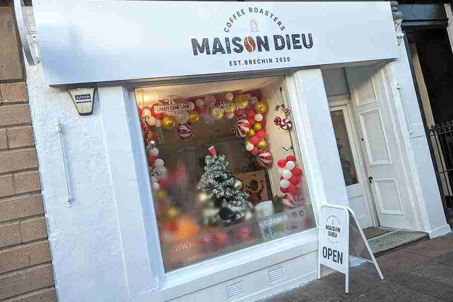 Storefront of Maison Dieu Coffee Roasters featuring a Christmas tree and festive decorations.